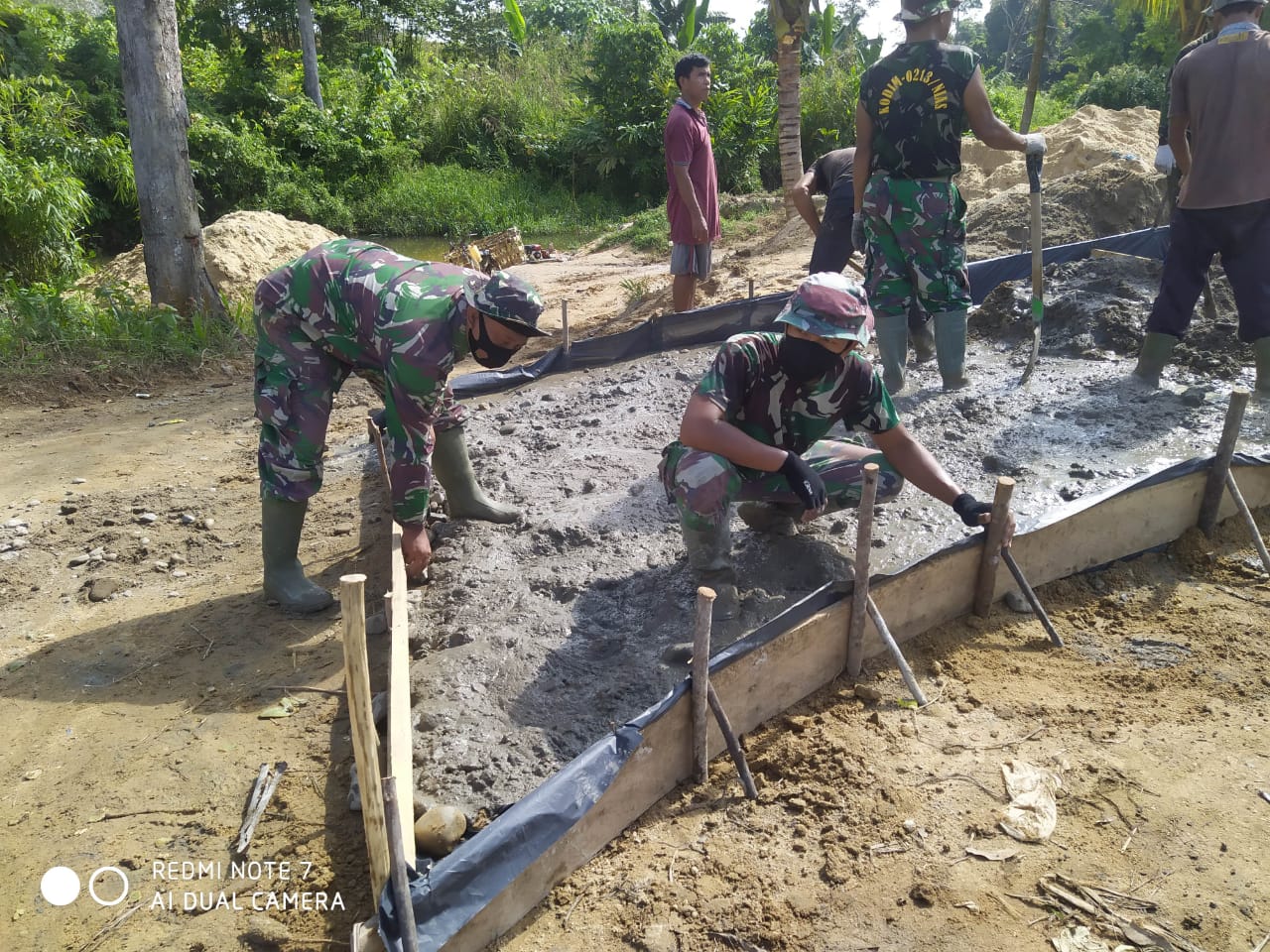Satgas TMMD dan Masyarakat Mendatarkan material Cor